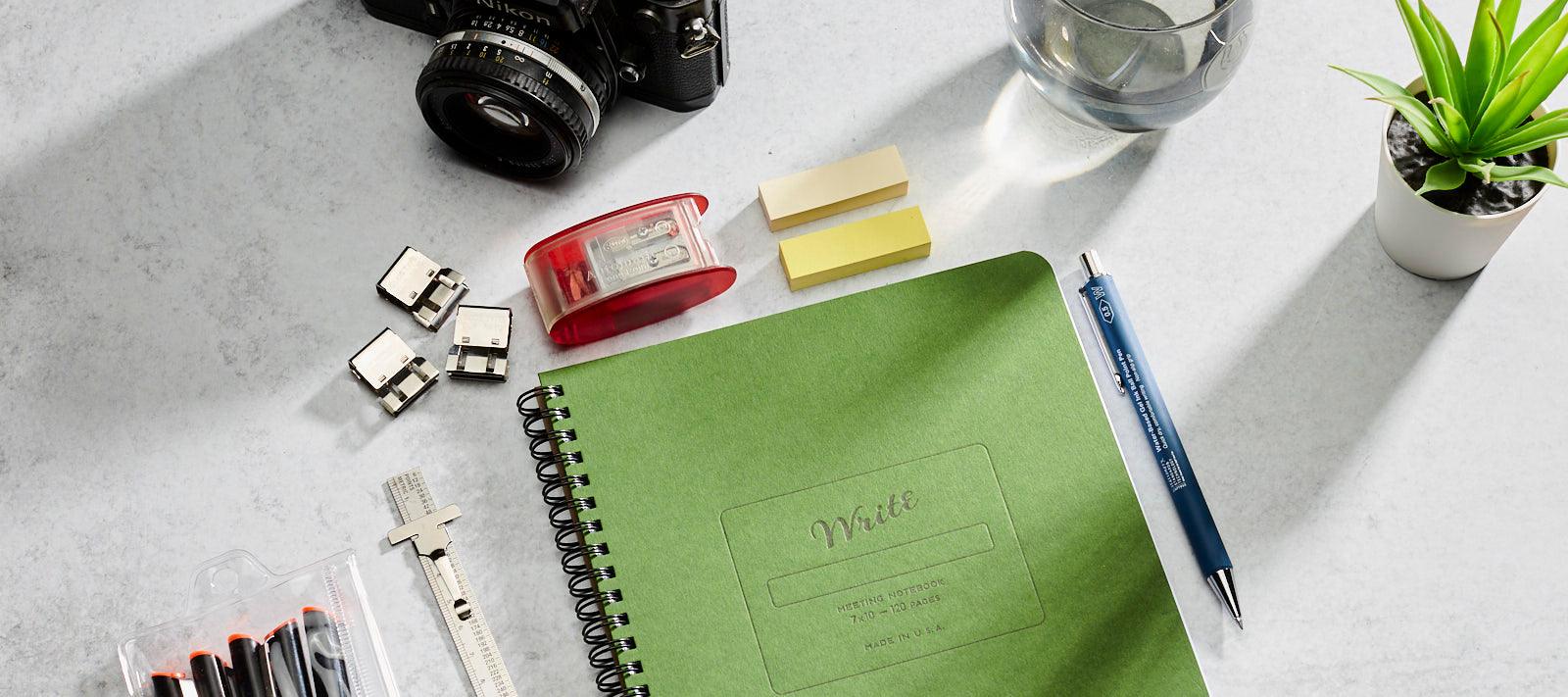 Notebook on a desk with pens and pencils